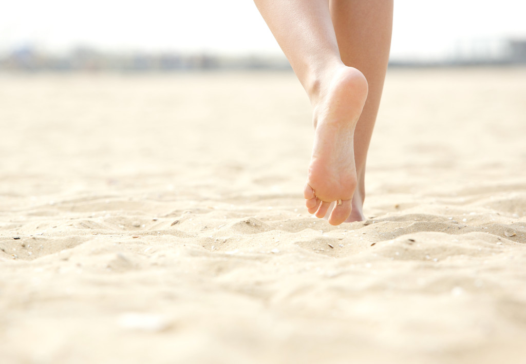Close up low angle woman barefoot walking on beach